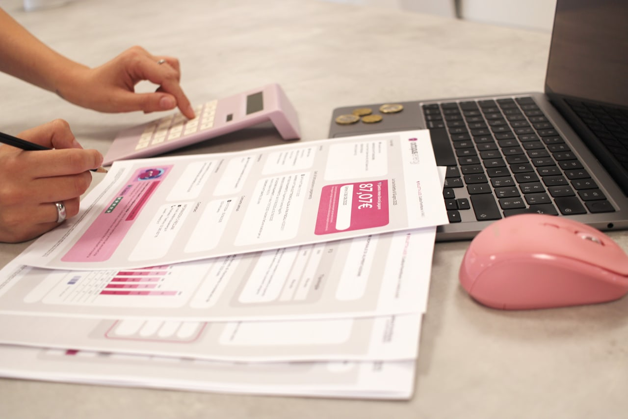 A small business owner calculating invoice payment terms with a calculator and paperwork