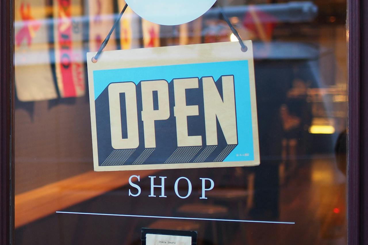 An open sign hanging in the glass door of a small shop